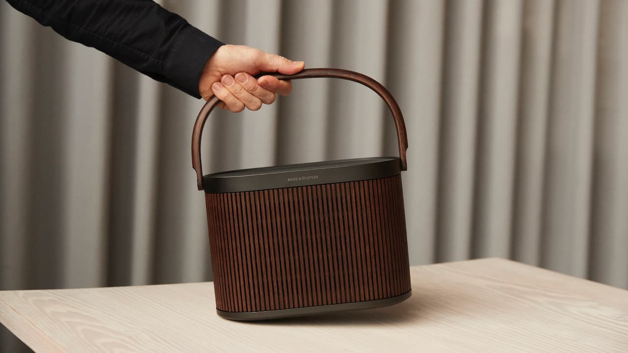 Person grabbing Bang & Olufsen Beosound A5 Portable Speaker in Dark Oak by the handle